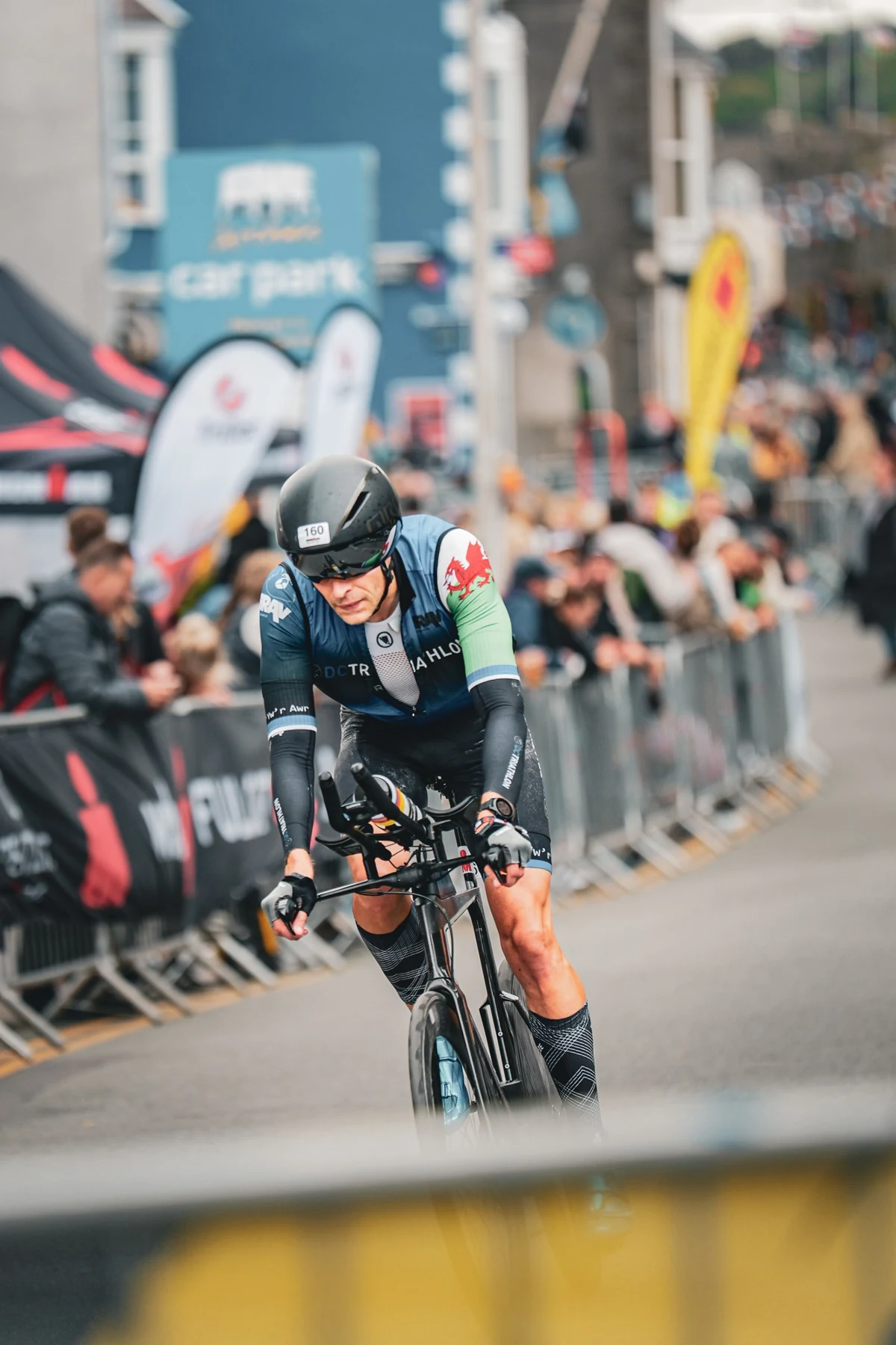 A road cyclist approaching the camera with a softly blurred crowd behind