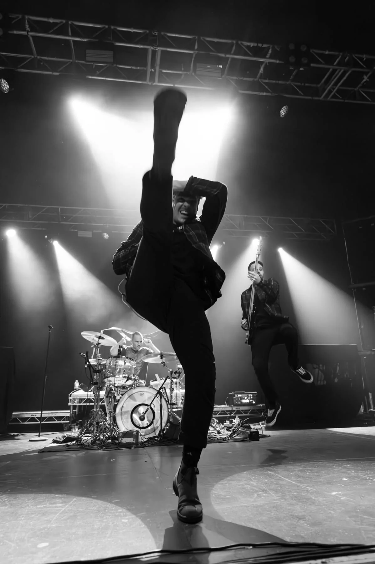 A performer high-kicking towards the camera under bright stage lights, in black and white