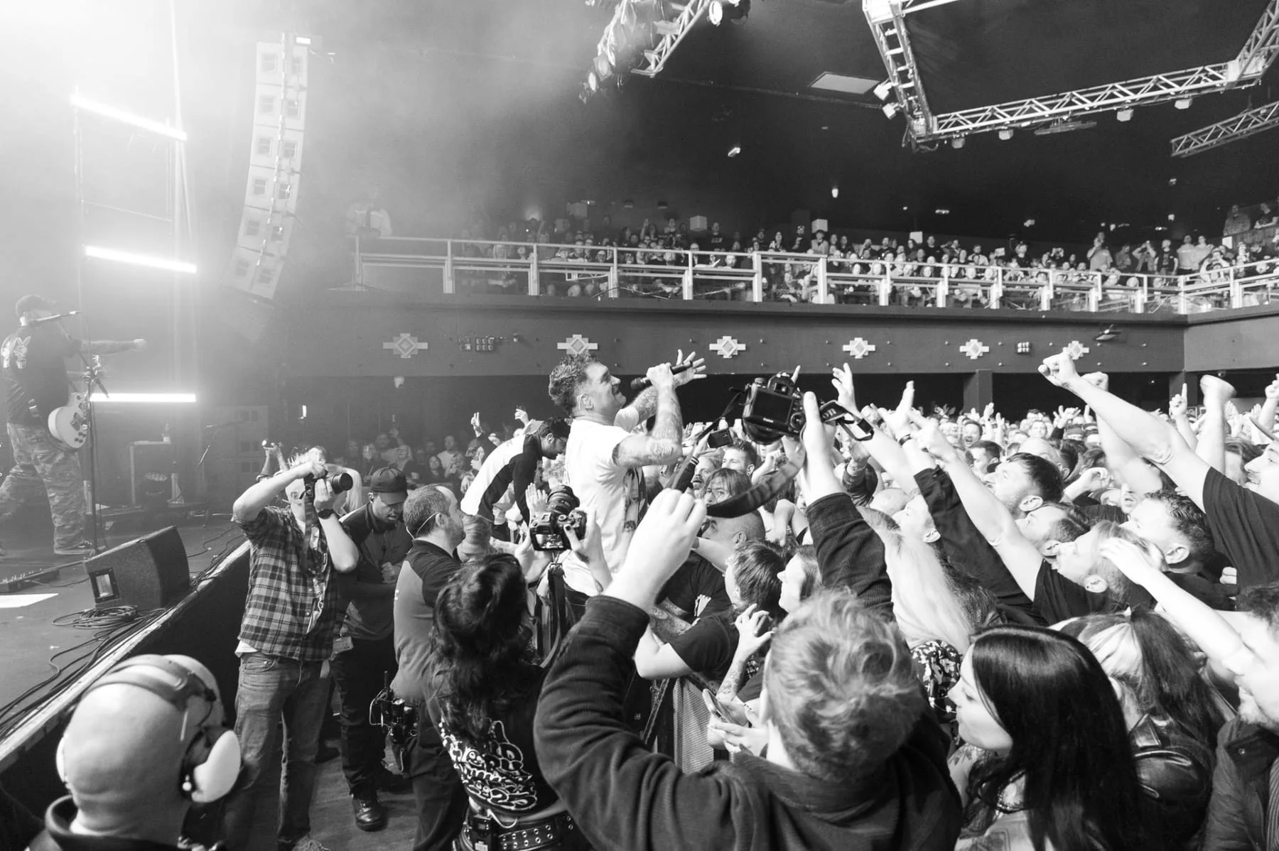 A singer reaching into an animated crowd in a black and white concert photograph